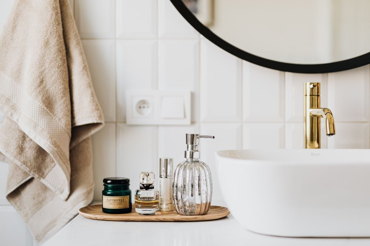 Interior of modern bathroom with various cosmetic products placed near sink with stylish faucet