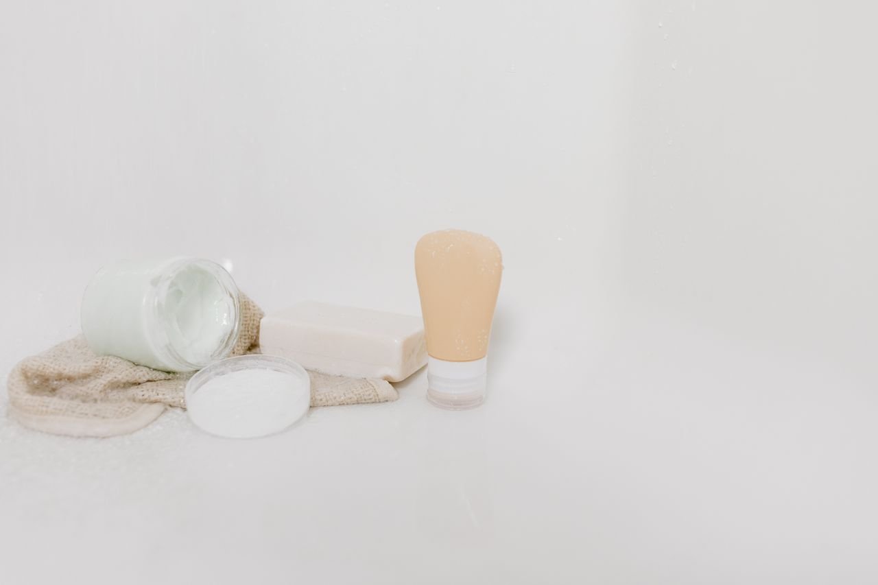 Minimalist setup of skincare products including cream, soap, and lotion on a white surface for beauty and self-care themes.